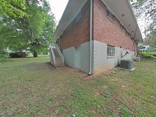 view of side of home with central AC unit and a yard