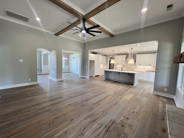 unfurnished living room featuring light wood-type flooring, beam ceiling, coffered ceiling, ornamental molding, and ceiling fan