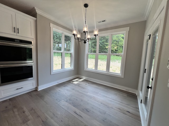 unfurnished dining area with crown molding, a chandelier, and light hardwood / wood-style flooring