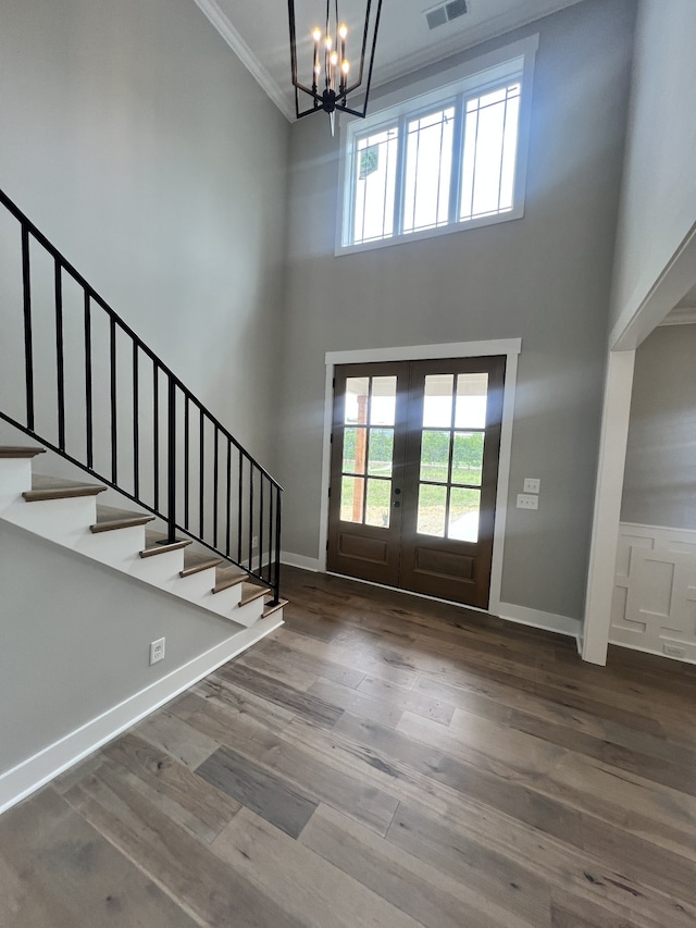 entryway featuring wood-type flooring, crown molding, a high ceiling, and a chandelier