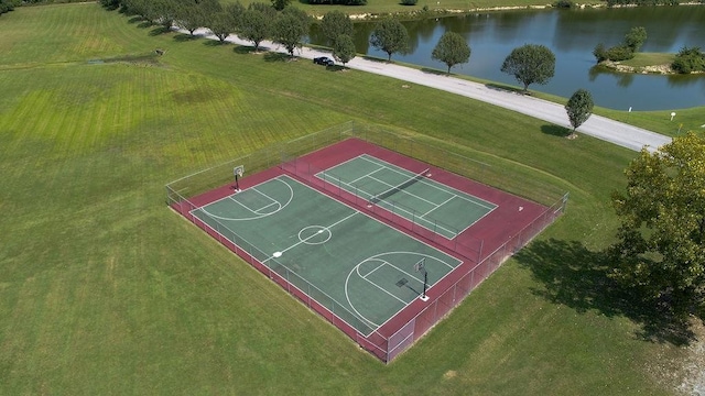 view of sport court with a water view and a yard