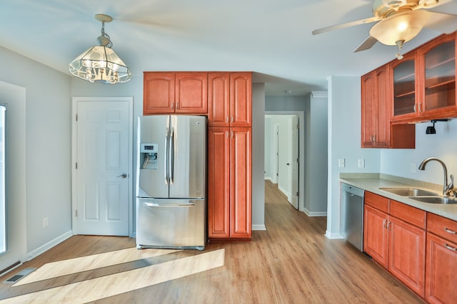 kitchen featuring stainless steel appliances, an inviting chandelier, hanging light fixtures, sink, and light wood-type flooring