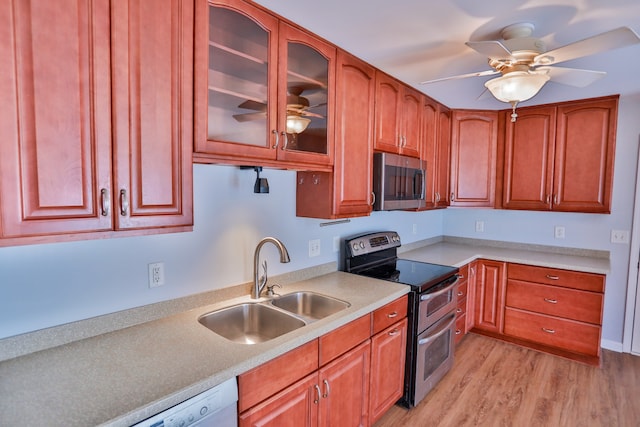 kitchen featuring light wood-type flooring, appliances with stainless steel finishes, sink, and ceiling fan