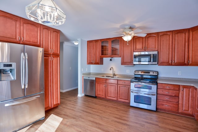 kitchen featuring stainless steel appliances, light wood-type flooring, pendant lighting, sink, and ceiling fan