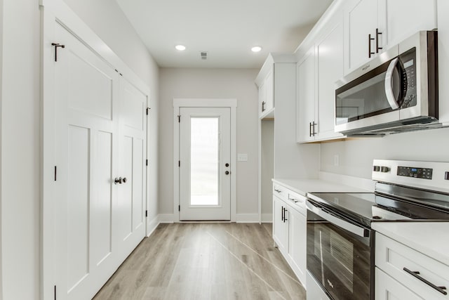 kitchen with white cabinets, stainless steel appliances, and light wood-type flooring