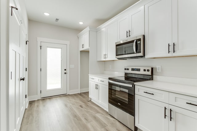 kitchen with white cabinets, a wealth of natural light, light wood-type flooring, and appliances with stainless steel finishes