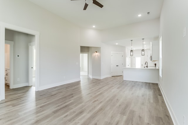 unfurnished living room with ceiling fan, sink, and light hardwood / wood-style floors