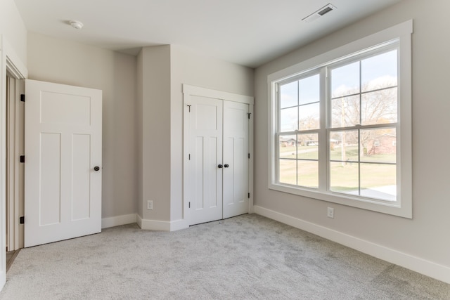 unfurnished bedroom featuring multiple windows, a closet, and light colored carpet