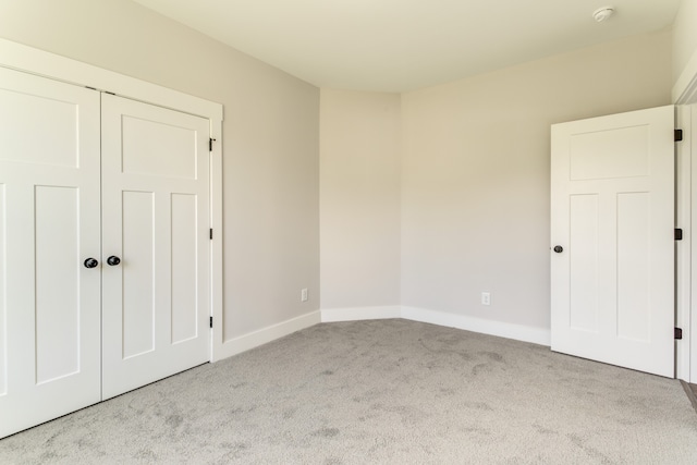 unfurnished bedroom featuring light colored carpet and a closet