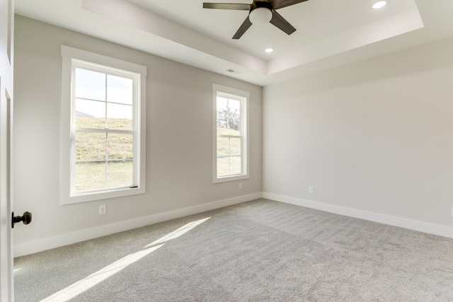 carpeted spare room featuring ceiling fan and a tray ceiling