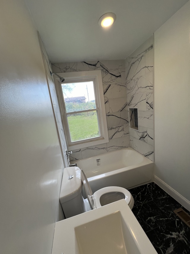 bathroom with tiled shower / bath combo and toilet