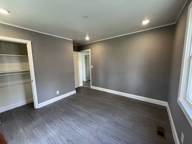 unfurnished bedroom featuring a closet, dark hardwood / wood-style floors, and ornamental molding