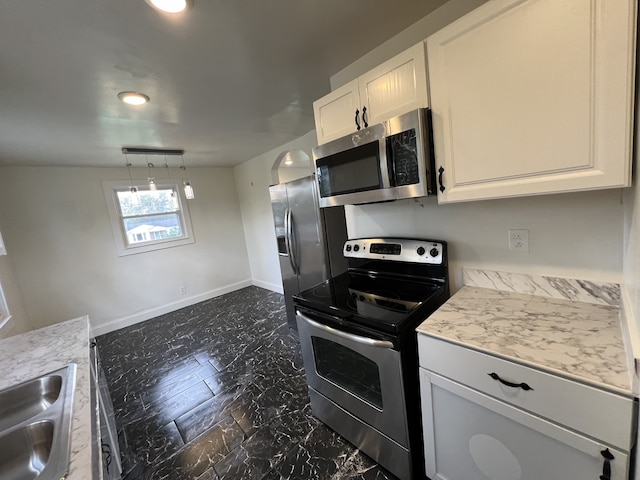 kitchen with appliances with stainless steel finishes, white cabinetry, vaulted ceiling, decorative light fixtures, and sink