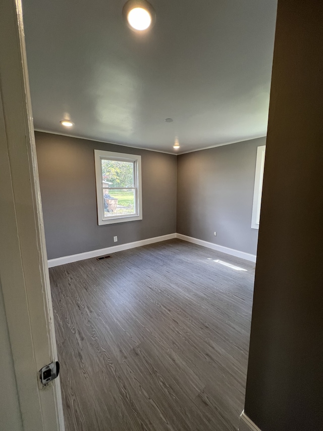 empty room with ornamental molding and dark wood-type flooring