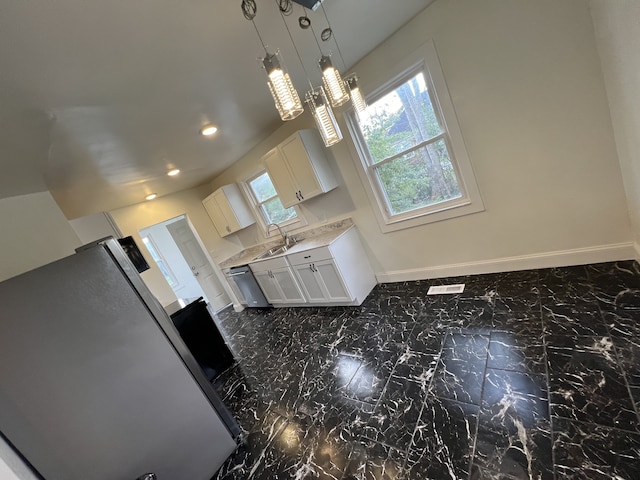 interior space with a healthy amount of sunlight, stainless steel fridge, white cabinetry, and pendant lighting