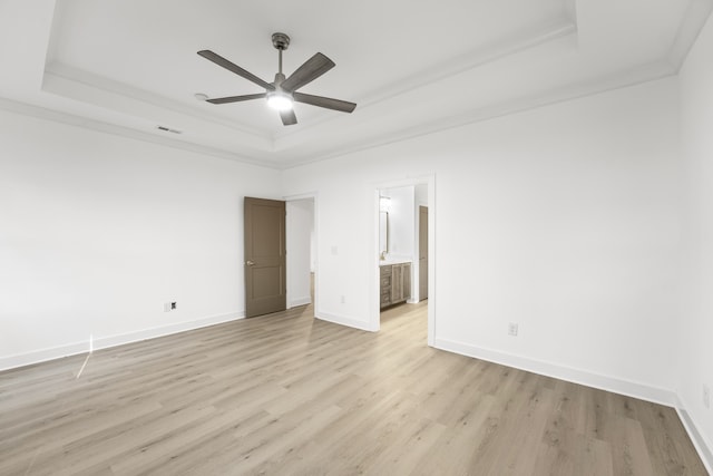 unfurnished room with light wood-type flooring, a raised ceiling, crown molding, and ceiling fan