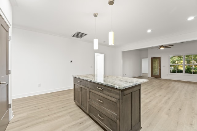 kitchen with light stone counters, light wood-type flooring, a center island, ceiling fan, and decorative light fixtures