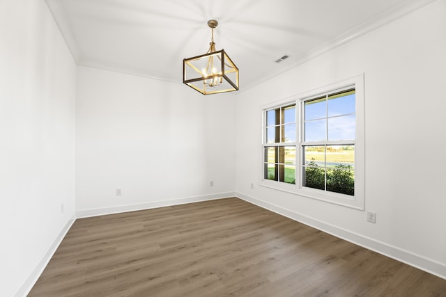 empty room with an inviting chandelier, ornamental molding, and dark wood-type flooring