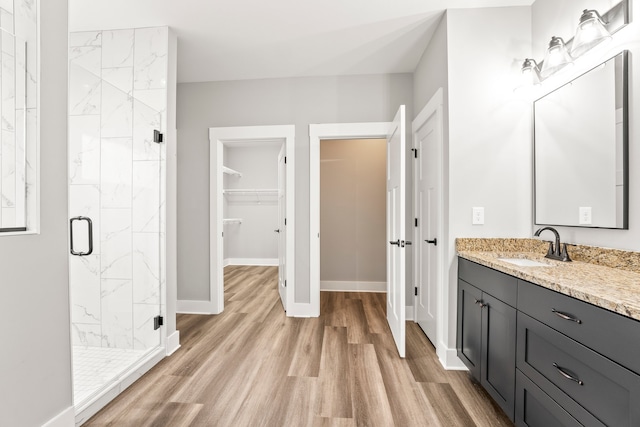 bathroom featuring wood-type flooring, vanity, and a shower with shower door