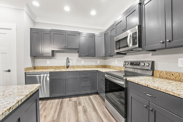 kitchen with gray cabinets, light hardwood / wood-style floors, appliances with stainless steel finishes, and sink