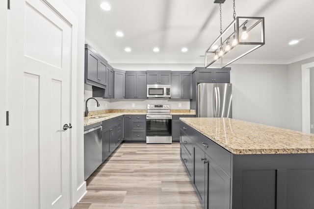 kitchen featuring light hardwood / wood-style floors, a kitchen island, pendant lighting, stainless steel appliances, and sink