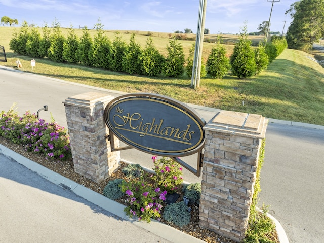 community / neighborhood sign featuring a lawn and a rural view