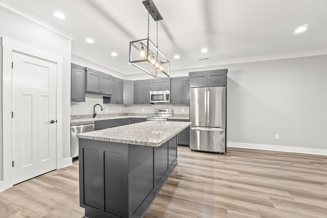 kitchen featuring a center island, light hardwood / wood-style floors, appliances with stainless steel finishes, and decorative light fixtures