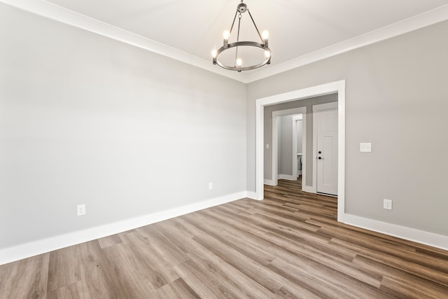 unfurnished room with a notable chandelier, wood-type flooring, and ornamental molding