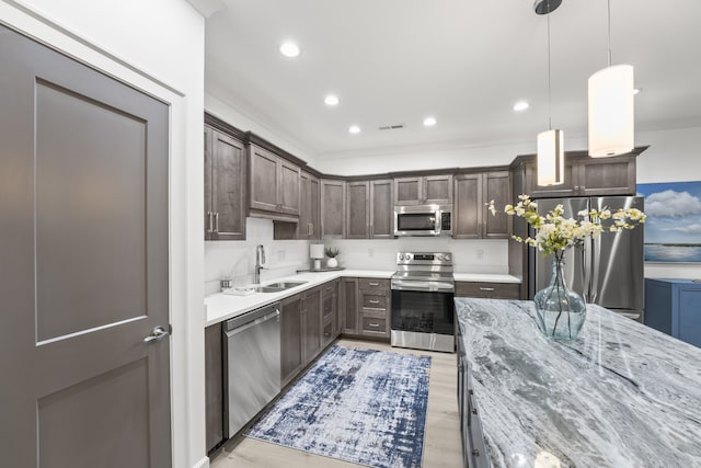 kitchen with dark brown cabinets, light wood-type flooring, appliances with stainless steel finishes, and sink