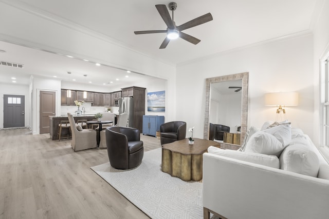 living room featuring ceiling fan, ornamental molding, and light hardwood / wood-style floors