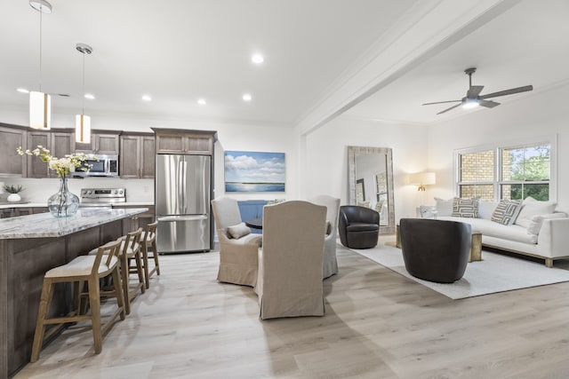 living room featuring ceiling fan, light hardwood / wood-style flooring, and crown molding