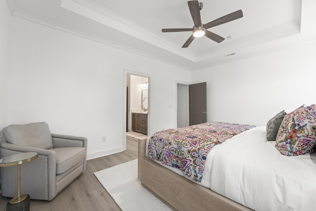 bedroom featuring light wood-type flooring, a raised ceiling, crown molding, and ceiling fan