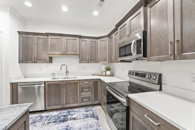 kitchen with light hardwood / wood-style flooring, appliances with stainless steel finishes, dark brown cabinetry, and sink