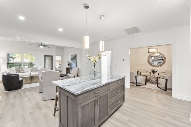 kitchen featuring light hardwood / wood-style floors, ceiling fan, light stone counters, and decorative light fixtures