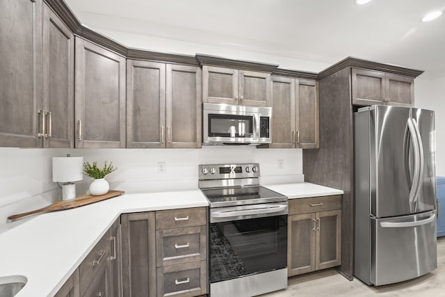 kitchen featuring dark brown cabinetry, appliances with stainless steel finishes, and light wood-type flooring