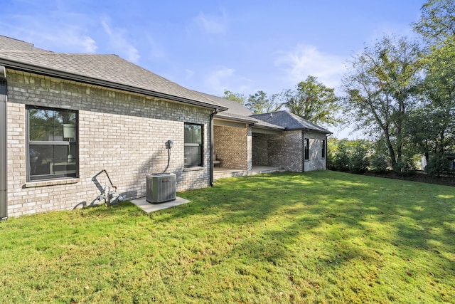 rear view of house featuring a lawn and central air condition unit