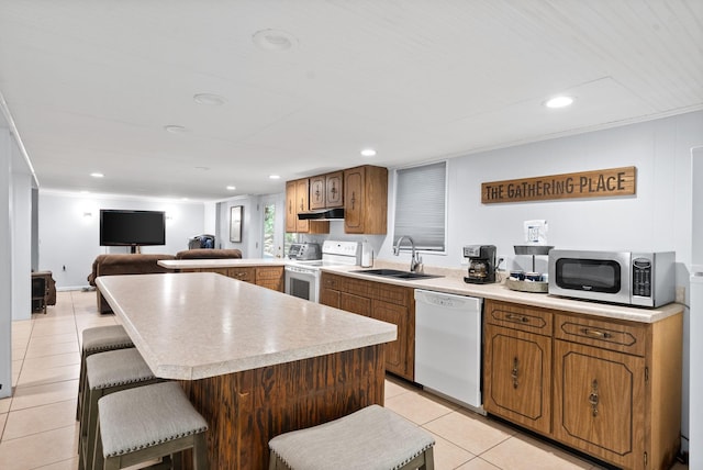 kitchen featuring light countertops, white appliances, under cabinet range hood, a sink, and light tile patterned floors