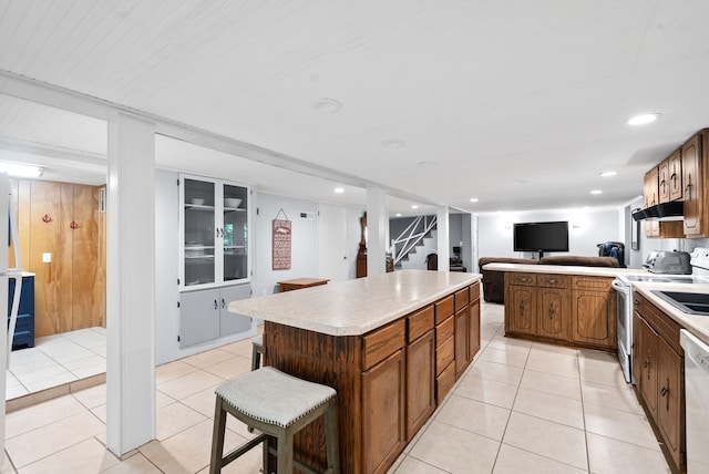 kitchen featuring a kitchen bar, white electric range, a center island, and light tile patterned floors