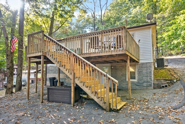 back of house featuring stone siding, stairway, a deck, and central air condition unit