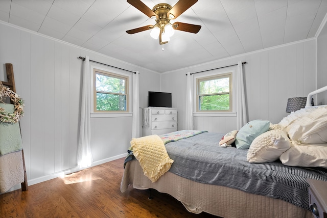 bedroom featuring ceiling fan, hardwood / wood-style flooring, ornamental molding, and multiple windows