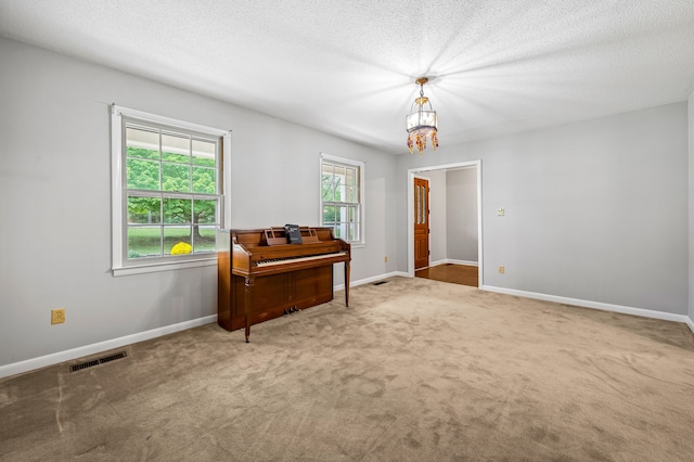 misc room featuring carpet floors, an inviting chandelier, and a textured ceiling