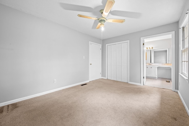 unfurnished bedroom featuring connected bathroom, ceiling fan, and light colored carpet