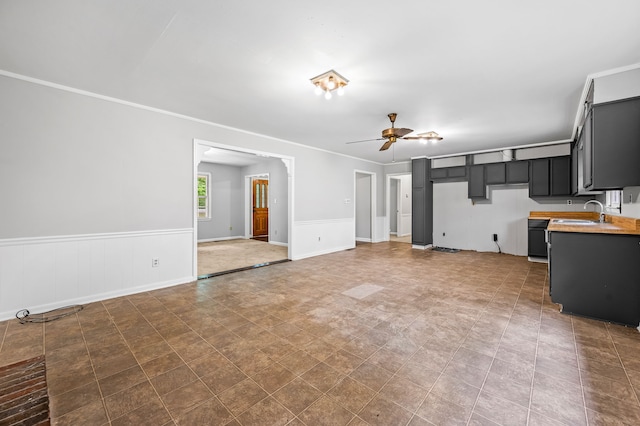 unfurnished living room featuring ceiling fan, crown molding, and sink