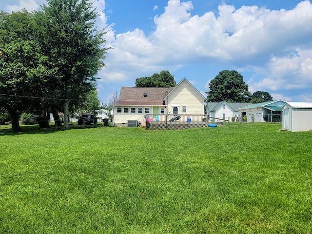 back of property with a deck, central air condition unit, and a lawn