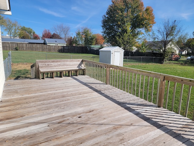 wooden terrace with a storage shed and a lawn