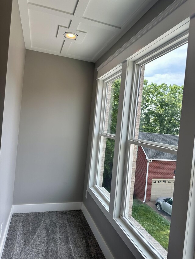 spare room with coffered ceiling and dark colored carpet