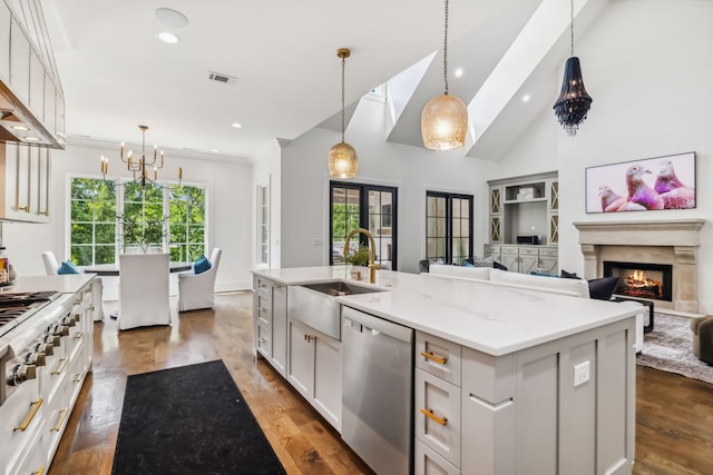 kitchen with appliances with stainless steel finishes, a kitchen island with sink, a premium fireplace, dark hardwood / wood-style floors, and hanging light fixtures