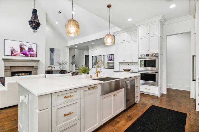 kitchen featuring a center island with sink, sink, hanging light fixtures, appliances with stainless steel finishes, and white cabinetry