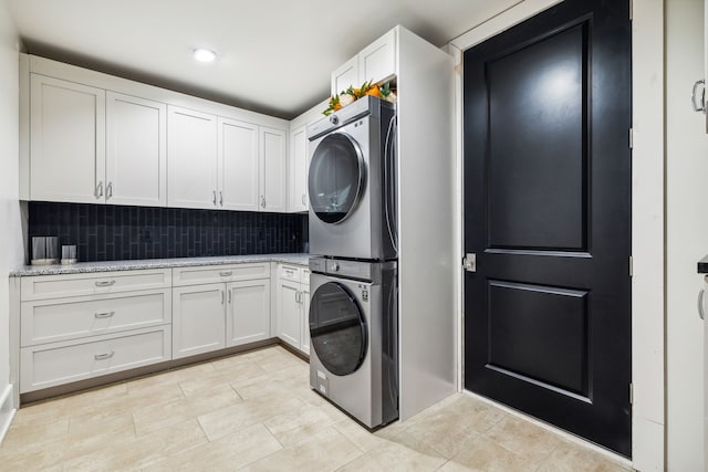 washroom with cabinets and stacked washer and clothes dryer