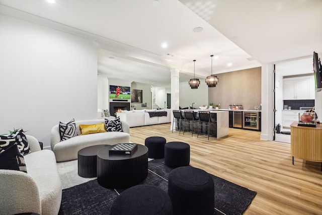 living room featuring light wood-type flooring, ornamental molding, and wine cooler